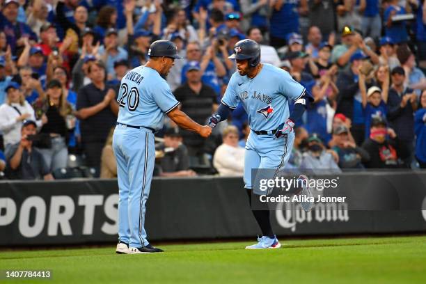 George Springer of the Toronto Blue Jays shakes hands with third base coach Luis Rivera after hitting a solo home run to center field during the...