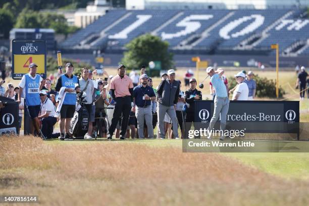 Justin Thomas of the United States plays his shot from the fourth tee as Tiger Woods of the United States looks on during a practice round prior to...