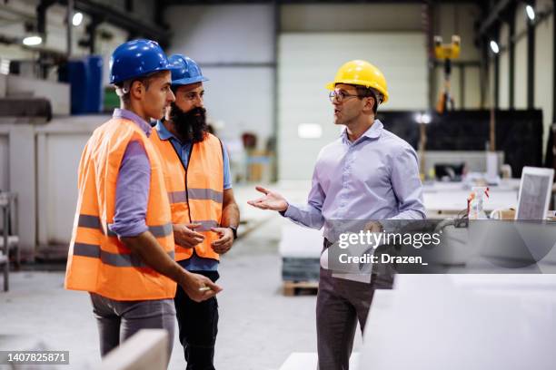 ingenieros en nave de fábrica, realizando control de calidad. ocupación de fabricación en nave industrial moderna, con procesos automatizados y robots. industria de procesamiento de metales y almacén. - seguridad y salud ocupacional fotografías e imágenes de stock