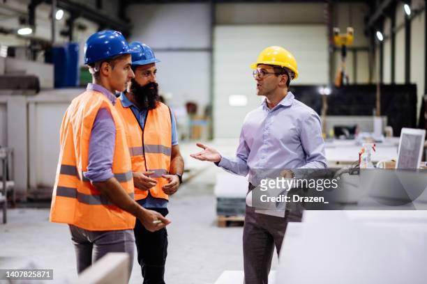 engineers in factory hall, performing quality control. manufacturing occupation in modern industrial hall, with automated process and robots. metal processing industry and warehouse. - health and safety stock pictures, royalty-free photos & images