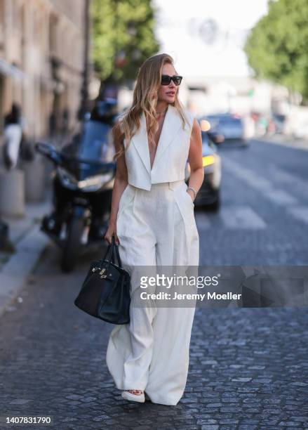 Ginta seen wearing back sunglasses from Yves Saint Laurent, diamond stud earrings, diamond necklace, a creme white linen suit vest and matching creme...