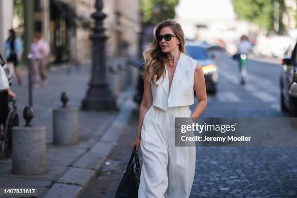 Ginta seen wearing back sunglasses from Yves Saint Laurent, diamond stud earrings, diamond necklace, a creme white linen suit vest and matchings...