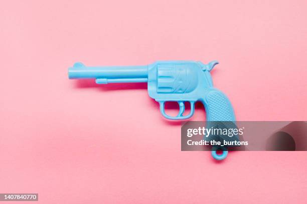 blue toy gun on pink background - pistolenschießen stock-fotos und bilder