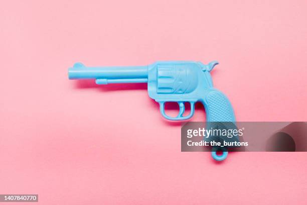 blue toy gun on pink background - arma de brinquedo imagens e fotografias de stock