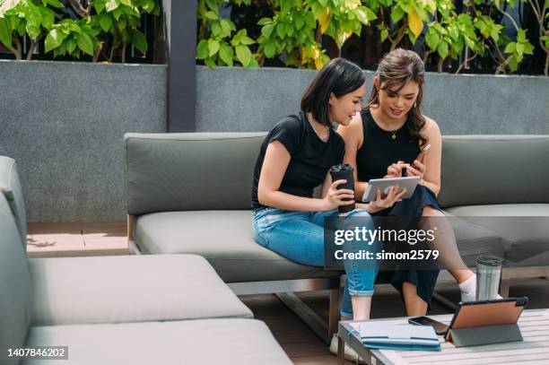 an asian female financial advisor using digital tablet showing best solution for her young clients at cozy outdoor lounge - star style lounge imagens e fotografias de stock