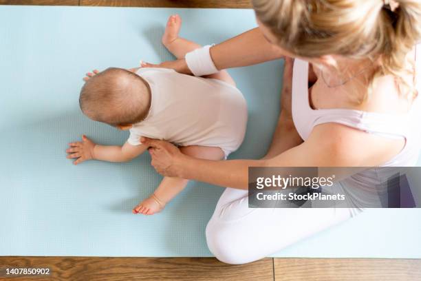 mother sitting on the floor and exercising at home whit her baby - child yoga elevated view stock pictures, royalty-free photos & images