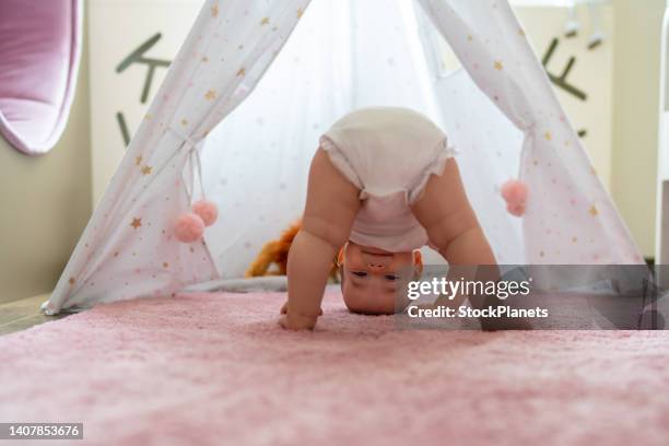 happy baby girl standing upside down on the carpet at home - beautiful barefoot girls imagens e fotografias de stock