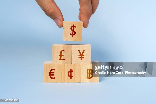 hand picking dollar sign on wood block with currency symbol - yen sign stock-fotos und bilder