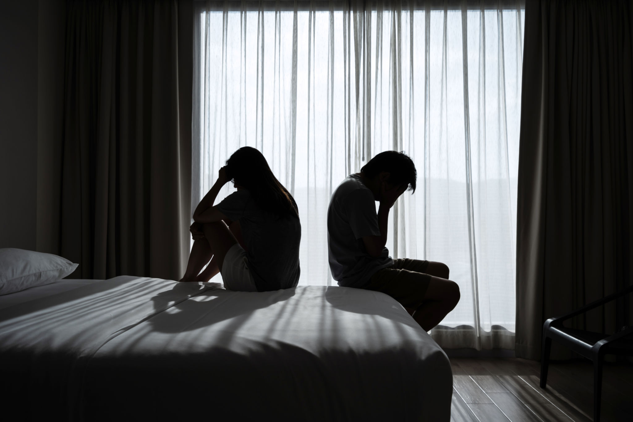 Depressed couple having a problem sitting head in hands in the dark bedroom, Negative emotion and mental health concept Depressed couple having a problem sitting head in hands in the dark bedroom, Negative emotion and mental health concept