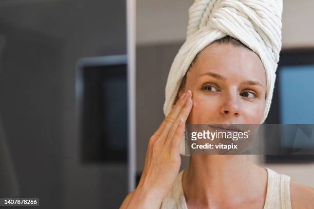 woman applying moisturizing face cream - applicera bildbanksfoton och bilder