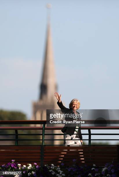 Presenter Sue Barker waves to the crowd as they walk over the bridge on day fourteen of The Championships Wimbledon 2022 at All England Lawn Tennis...