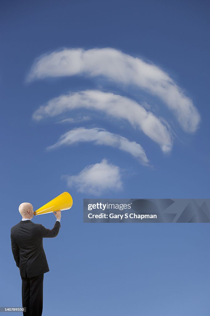 Businessman with megaphone lifted to wi-fi cloud