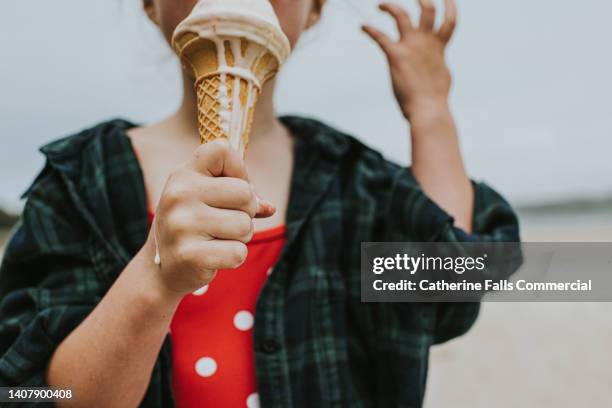 close-up of a little girl licking a melting ice-cream. focus is on her little hand, now sticky from the melting ice-cream. - girl eating messy ice cream cone stock pictures, royalty-free photos & images