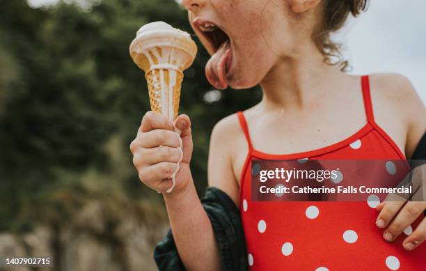 close-up of a little girl licking a melting ice-cream. focus is on her little hand, now sticky from the melting ice-cream. - girl eating messy ice cream cone stock pictures, royalty-free photos & images