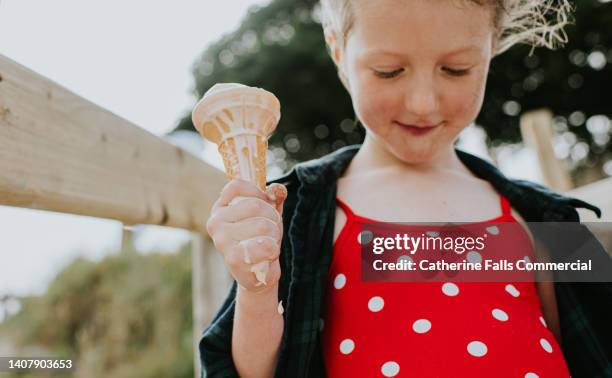 a child enjoys a melting ice-cream in a sunny outdoor environment. - girl eating messy ice cream cone stock pictures, royalty-free photos & images