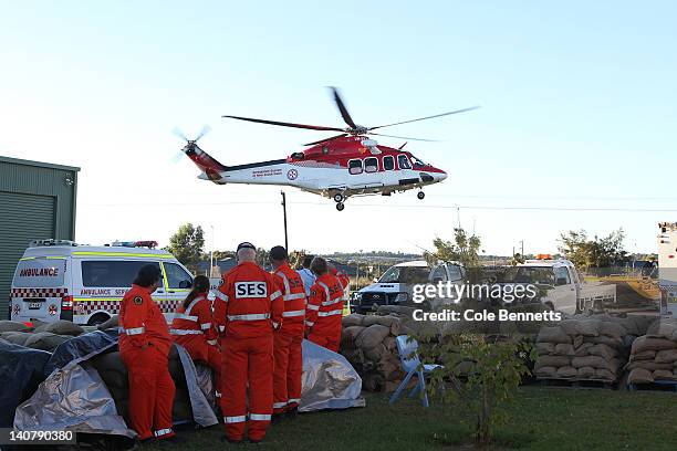Crew look on as the NSW Ambulance rescue helicopter takes off on March 7, 2012 in Wagga Wagga, Australia. 9000 evacuated residents are waiting for...