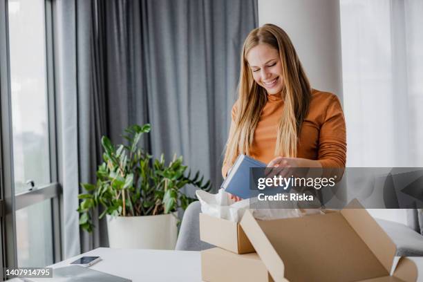 smiling woman opening a delivery box - receiving parcel stock pictures, royalty-free photos & images