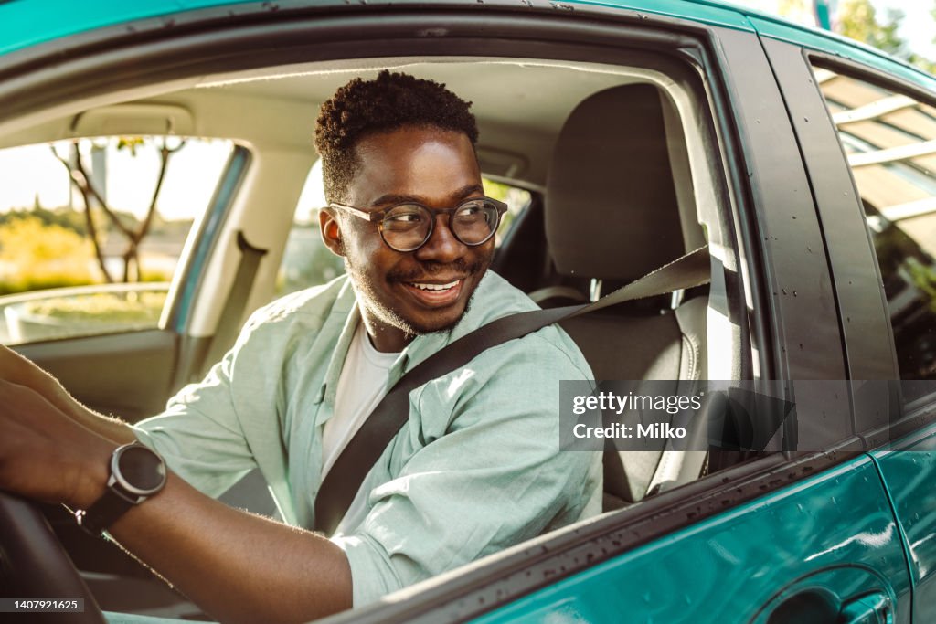 Feliz motorista afro-americano dirigindo um carro e olhando pela janela do carro