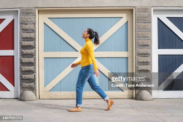 woman walking by colorful doors outside - jeans neri foto e immagini stock