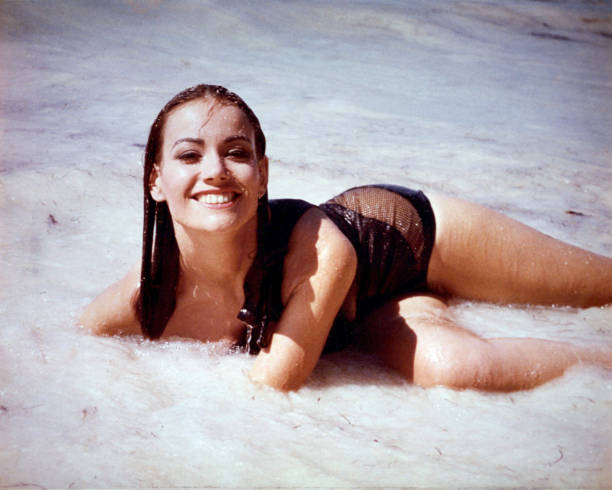 Claudine Auger, French actress, wearing a brown swimsuit posing in the surf in a publicity portrait issued for the film, 'Thunderball', 1965. The...