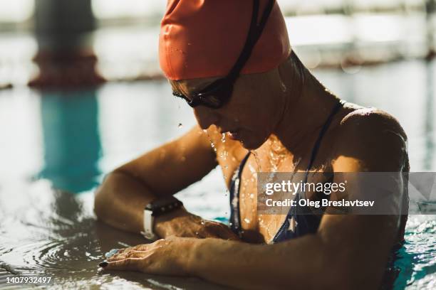 tired and exhausted athlete woman on edge of swimming pool after powerful endurance training - finale wedstrijd stockfoto's en -beelden