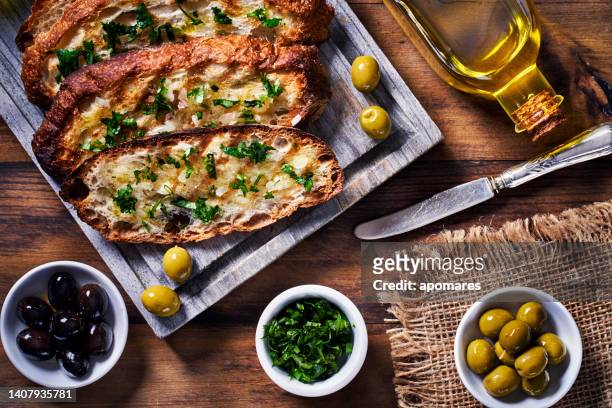 snack or appetizer of garlic basil and olive oil bruschetta on table in a rustic kitchen - pão de queijo prensado imagens e fotografias de stock