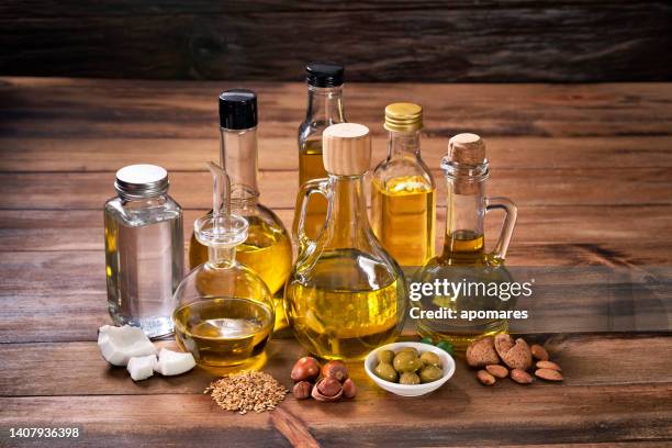 assorted healthy vegetable oil bottle collection on wooden table in a old fashioned kitchen with low key illumination - óleo de cozinha imagens e fotografias de stock