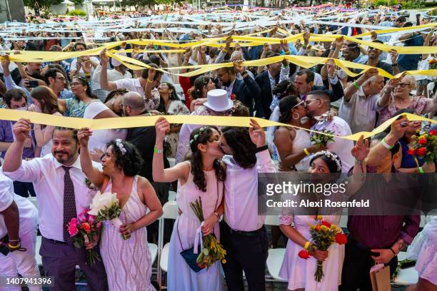 Couples kiss while holding a ribbon in the air during a unity ritual at the Wedding at Lincoln Center on July 10, 2022 in New York City. Lincoln...