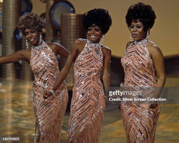 The Supremes , wearing matching sequinned peach dresses with silver necklaces and earrings, during a live concert performance, circa 1965.