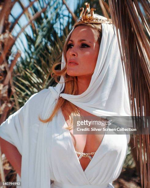 Ursula Andress, Swiss actress, wearing a white dress with a plunging neckline and a white headscarf over a gold tiara, in a publicity portrait issued...