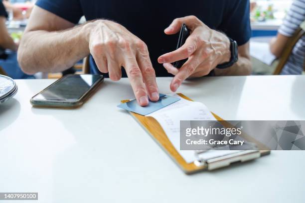 man prepares to pay restaurant bill with credit card - restaurant bill ストックフォトと画像