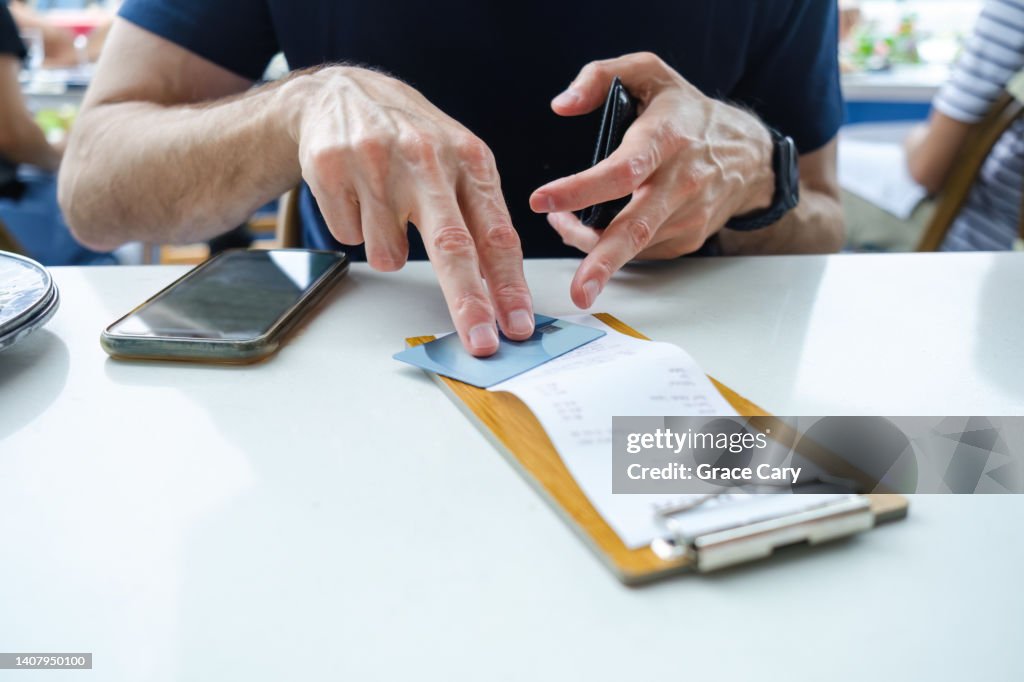 Man Prepares to Pay Restaurant Bill With Credit Card