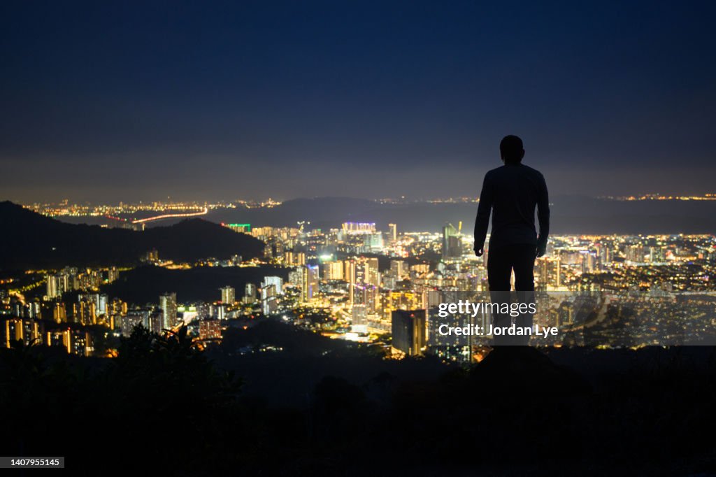 Man looking over cityscape at night, rear view