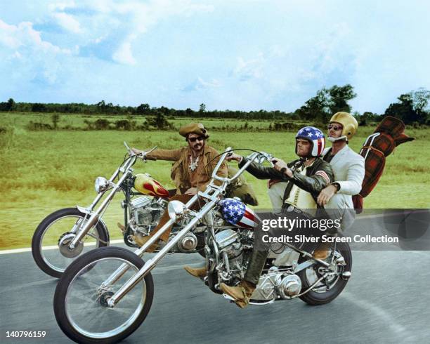 Dennis Hopper , US actor, and Peter Fonda, wearing a stars-and-stripes helmet, riding their chopper motorcycles, with Jack Nicholson, US actor,...