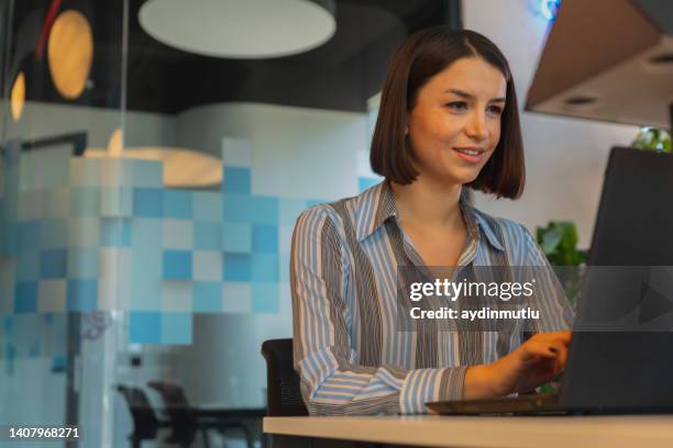 young business woman smiling an working behind acrylic glass sneeze wall guards in modern office during pandemic - woman coding stockfoto's en -beelden