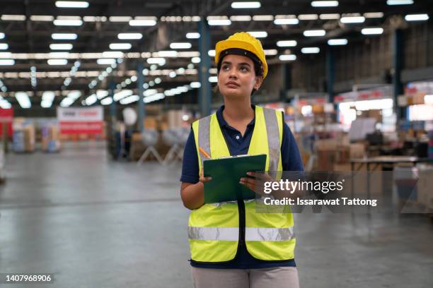 woman warehouse worker or supervisor with clipboard. girl looking for goods with a clipboard is checking inventory levels in a warehouse. logistics concept - south asian people stock pictures, royalty-free photos & images