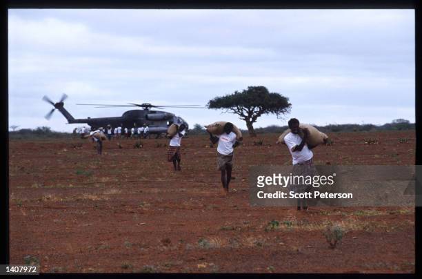 Men carry sacks of grain January 15, 1993 in Labatan Jirow, Somalia. US troops arrived in 1992 marking the beginning of a UN peacekeeping mission...