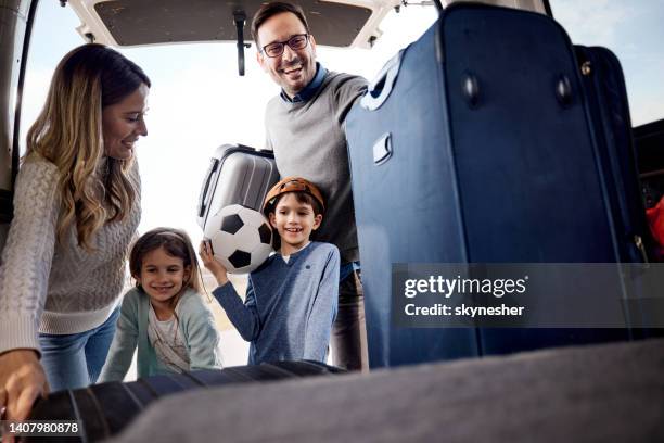 glückliche familie packt ihr gepäck in einen kofferraum. - luggage trunk stock-fotos und bilder