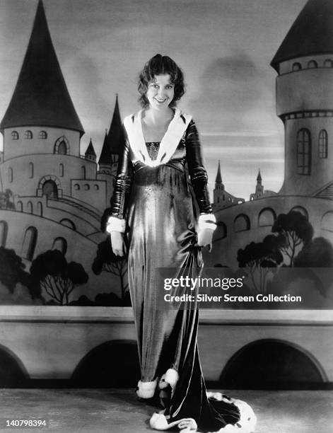 Full length portrait of Jeanette MacDonald , US singer and actress, wearing a full length dress ermine-trimmed dress, against a background of a...