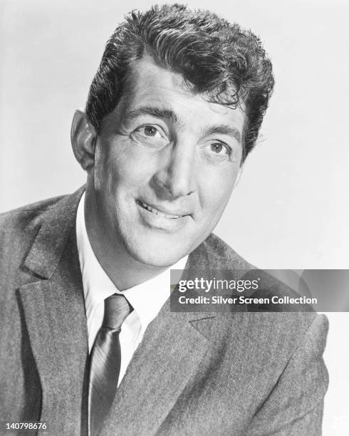 Dean Martin , US actor and singer, wearing a grey jacket over a white shirt with a dark tie, in a studio portrait, against a white background, circa...