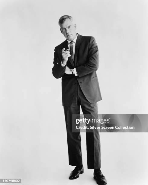 Full length portrait of Lee Marvin , US actor, wearing a black suit with a white shirt and a dark tie, in a studio portrait, against a white...