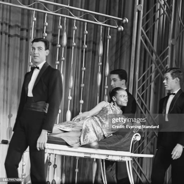 American actress, singer, and dancer Eartha Kitt carried onto the stage on a chaise longue by men during rehearsals for the Royal Variety Performance...