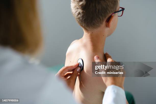 doctor checking boyâs lungs with a stethoscope - breath test stockfoto's en -beelden