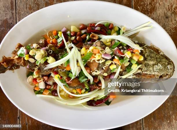 deep fried fish topping with mango and herbs salad dressing. - channidi foto e immagini stock