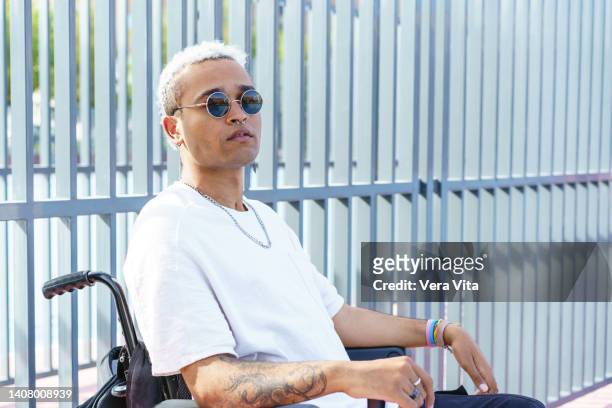 horizontal side portrait of disabled male with tattoos on wheelchair in urban clothes wearing sunglasses and white afro hair - man electric chair stock pictures, royalty-free photos & images