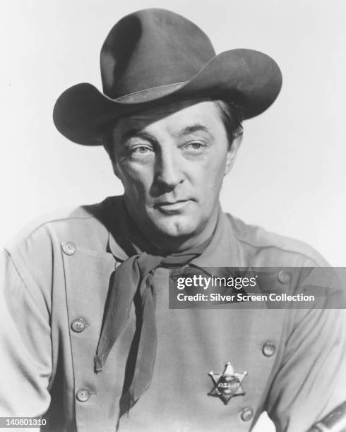 Robert Mitchum , US actor, wearing a cowboy hat, with a grey button-front tunic, a neckerchief, and a sheriff's badge, in a publicity portrait issued...