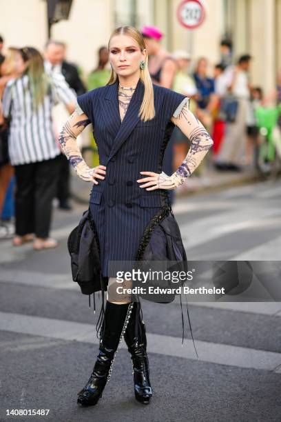 Guest wears diamonds and emeralds pendant earrings, a black striped print pattern sleeveless / buttoned jacket dress with embroidered black puffy...