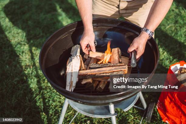 close up of a man starting campfire for bbq with ferro rod fire steel and fire wood - asian person bbq stock-fotos und bilder