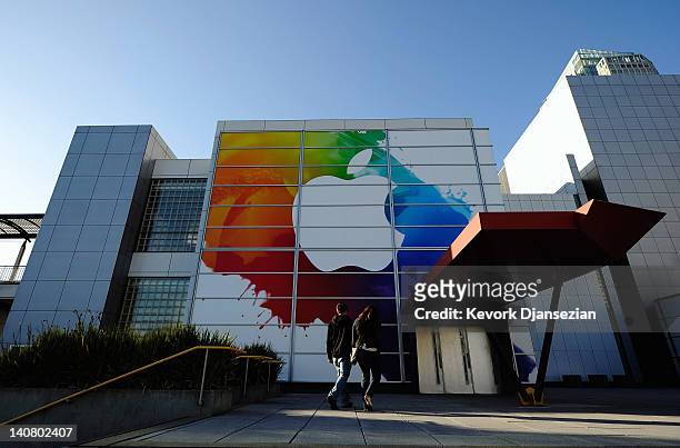People walk past large Apple sign placed at the front entrance of the Yerba Buena Center for the Arts in preperation for the unveiling of the new...