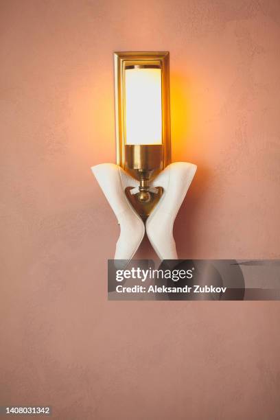 designer wedding shoes of the bride on a lamp or sconce, on a wall background, on a sunny day. women's new modern fashion high-heeled shoes made of genuine leather. morning preparations for the wedding. - wedding shoes stock pictures, royalty-free photos & images